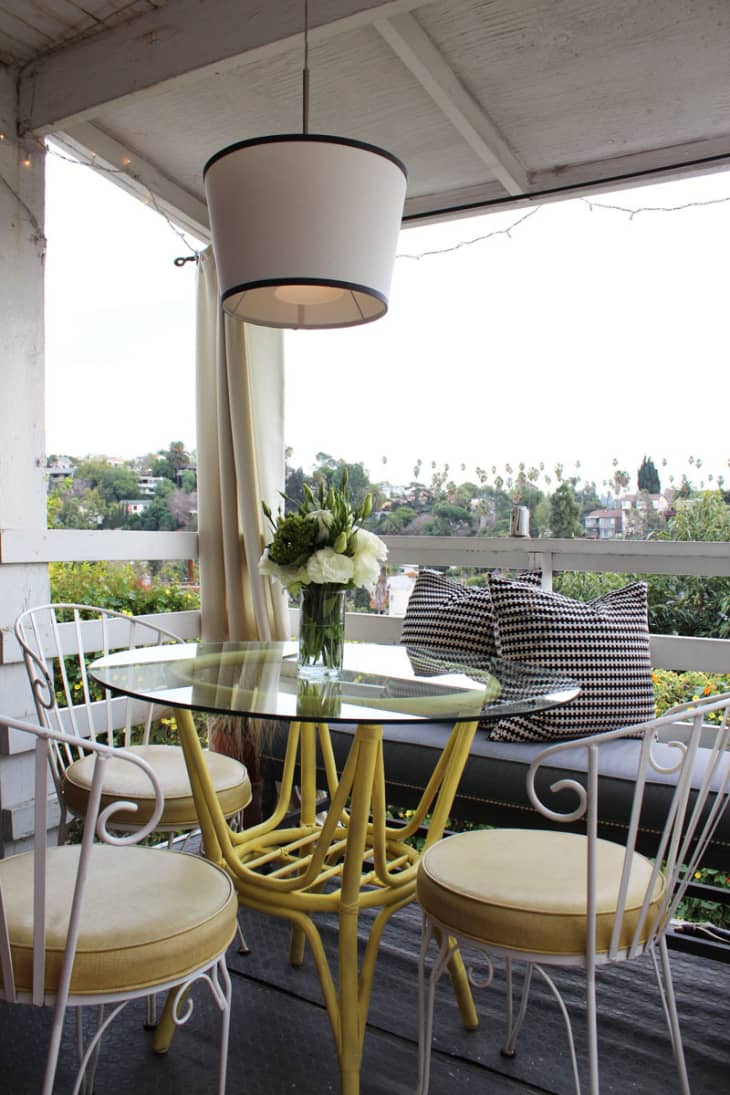 Covered condo patio with yellow table. summer outdoor decor trends